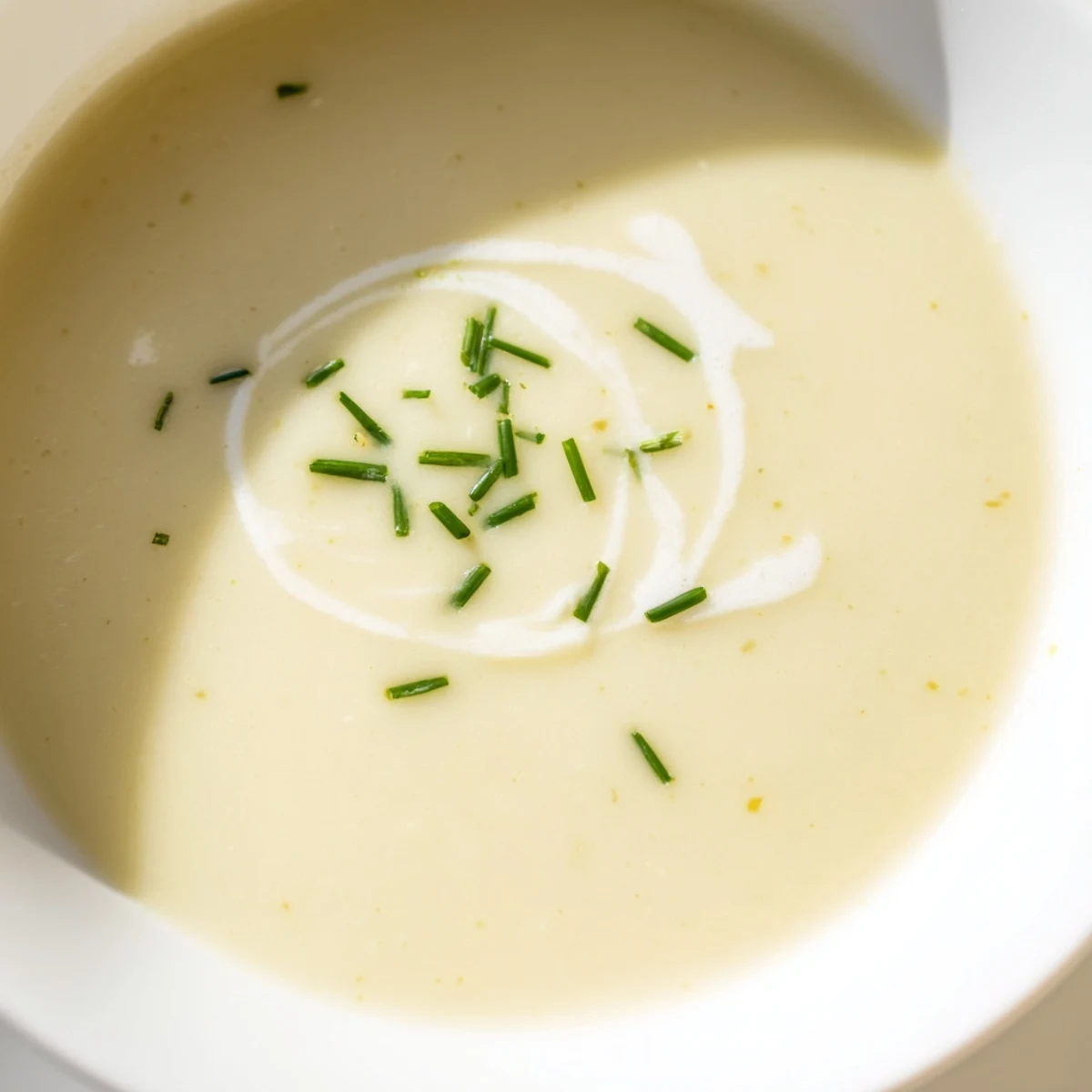 Close-up of Creamy Leek Soup with Diced Potatoes featuring tender vegetables and a swirl of fresh cream.