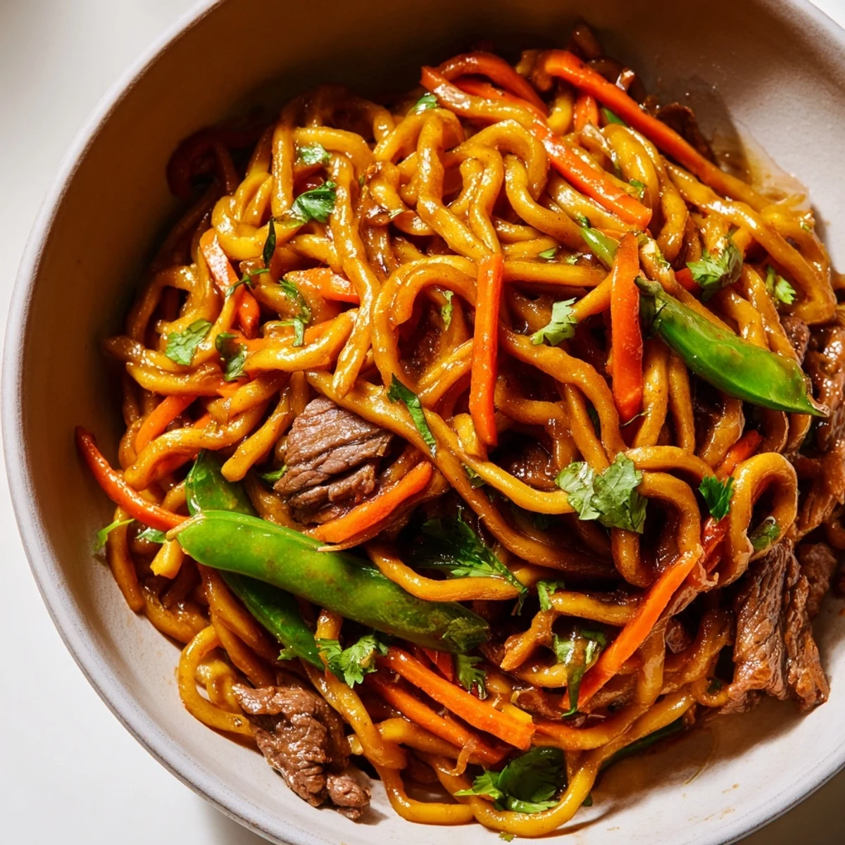 Freshly cooked Spicy Beef Noodles with Vegetables tossed in a hot wok with vibrant red peppers and snap peas.