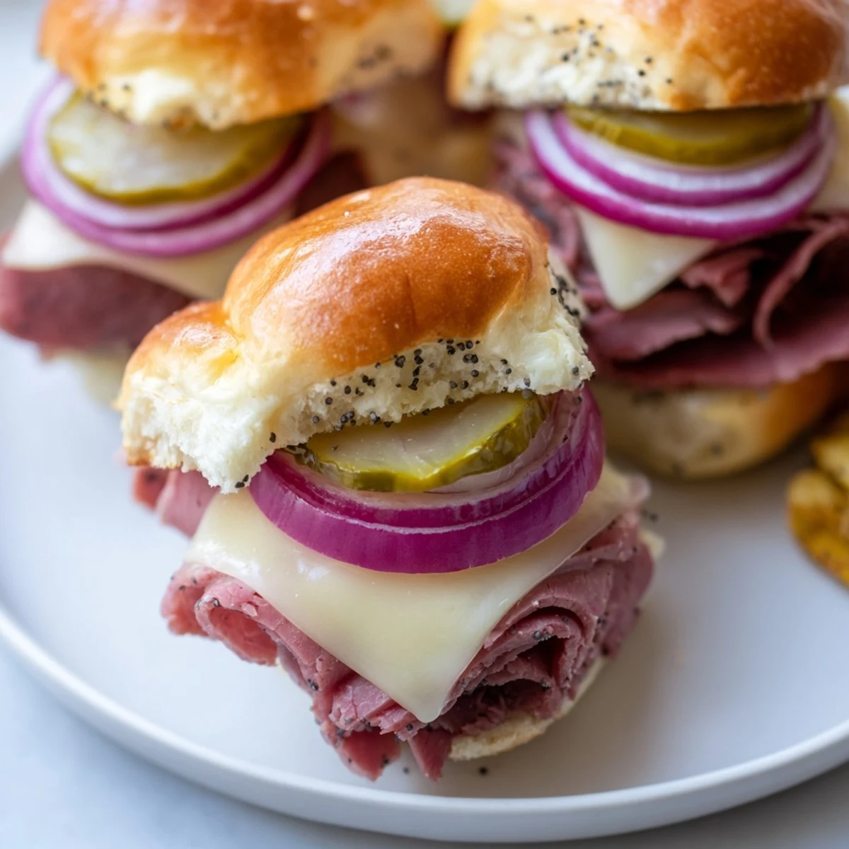 Freshly baked Corned Beef Sliders with melted Swiss cheese, tangy mustard, and thinly sliced red onion on golden slider buns.