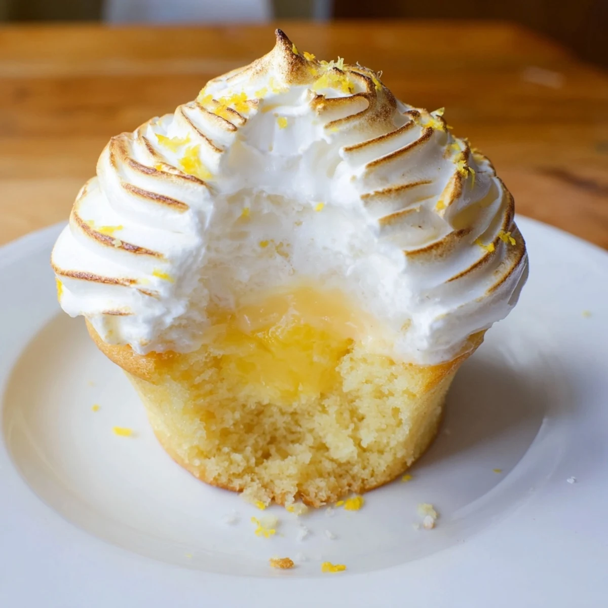 A close-up of Lemon Meringue Cupcakes reveals billowy, toasted meringue peaks that contrast beautifully with the tangy lemon curd inside the soft cupcake.