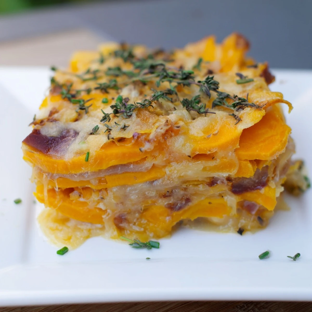 Layers of creamy Cheesy Sweet Potato Gratin with Caramelized Onions Delight topped with melted Gruyère and cheddar.