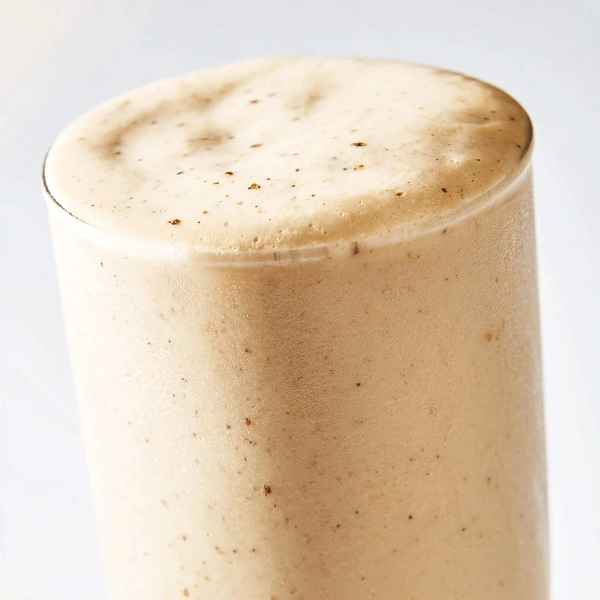 A frosty glass of Vanilla Bean Frappuccino topped with whipped cream and white chocolate shavings, perfect for a refreshing summer treat.