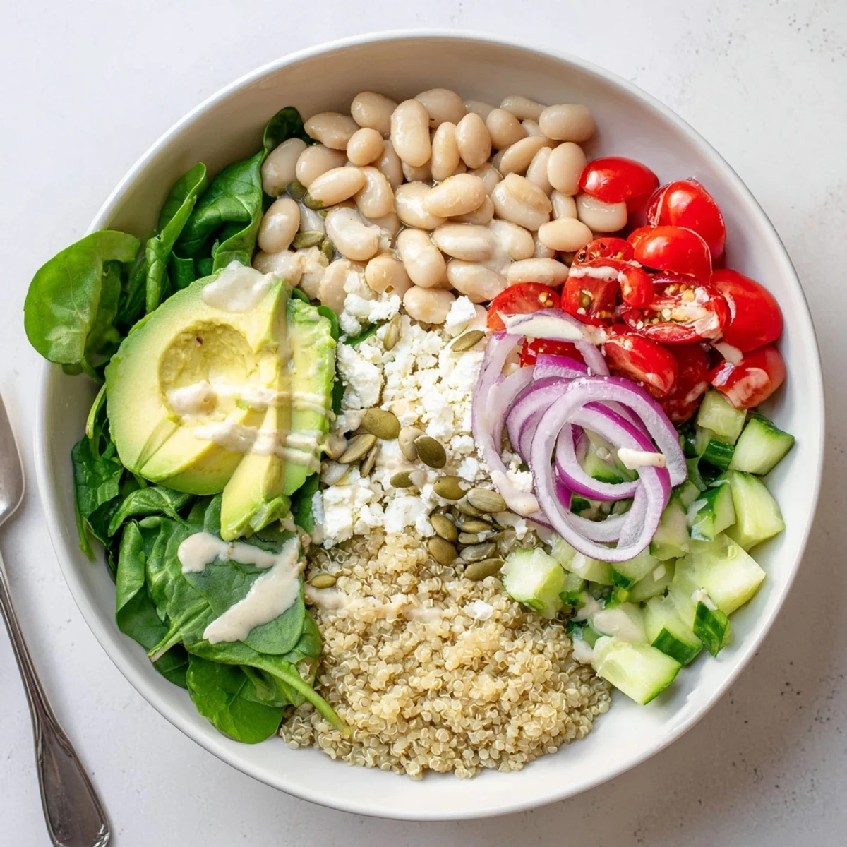 A close-up of the Spinach & White Bean Ultimate Protein Power Bowl with creamy avocado slices and pumpkin seeds.