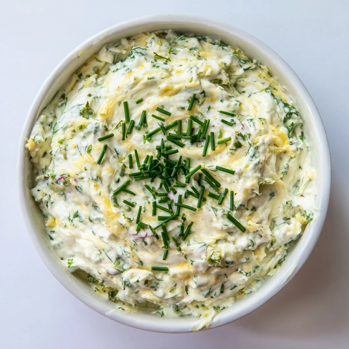 A close-up of Simple Easter Herb Cheese Dip featuring smooth texture, minced garlic, and lemon zest, served alongside crunchy crackers for an appetizer.