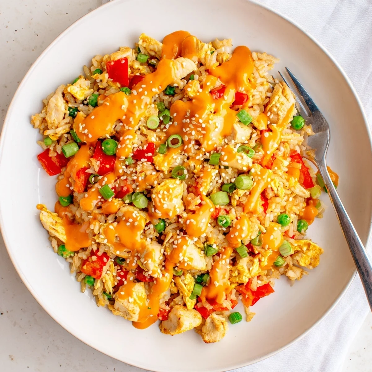Sizzling skillet of Bang Bang Fried Rice with chopped chicken, green onions, and a spicy, creamy sauce, ready to be served for dinner.