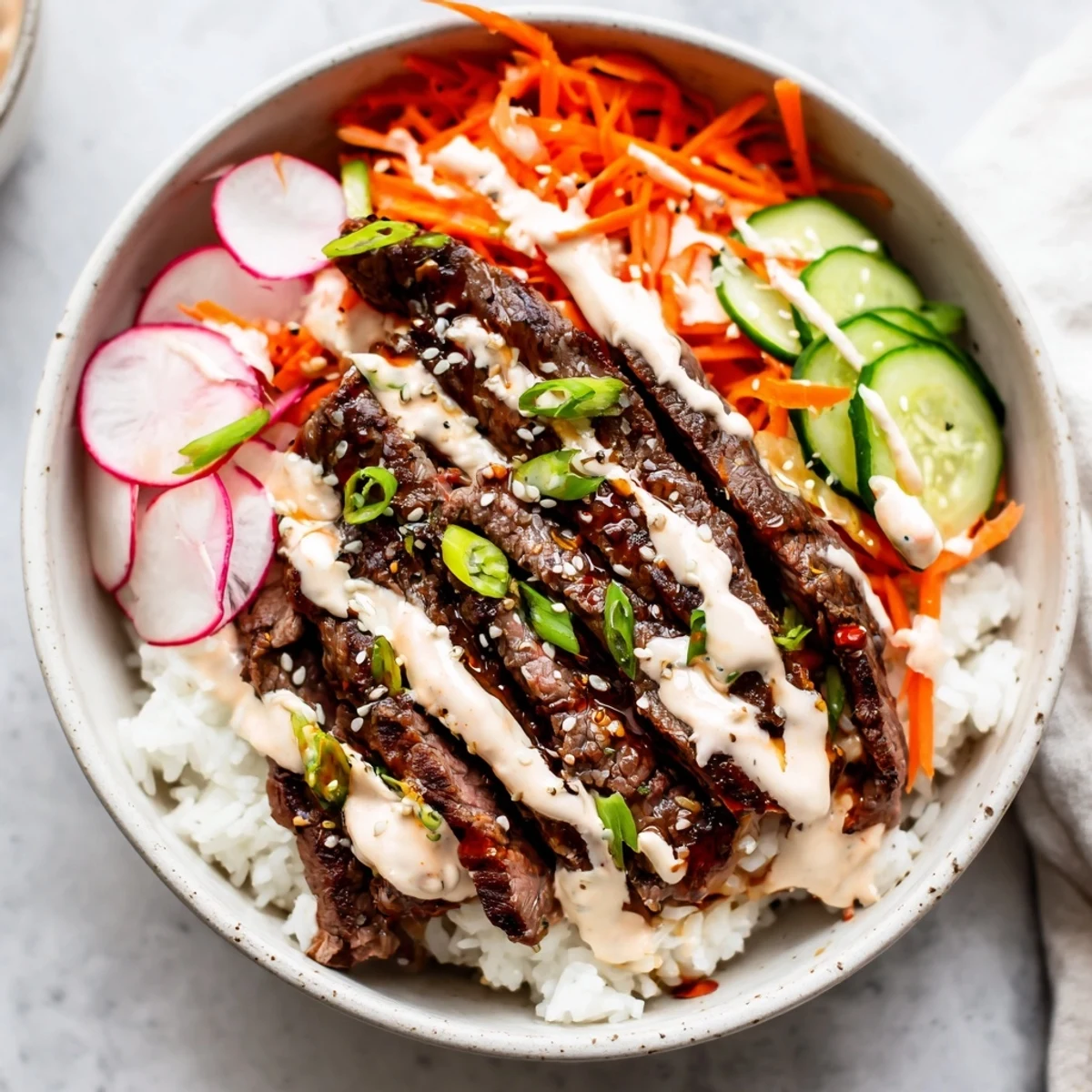 Tender beef slices glistening with Korean BBQ marinade sit atop fluffy white rice, drizzled with creamy spicy sauce for Irresistibly Easy Korean BBQ Steak Rice Bowls with Spicy Cream Sauce.