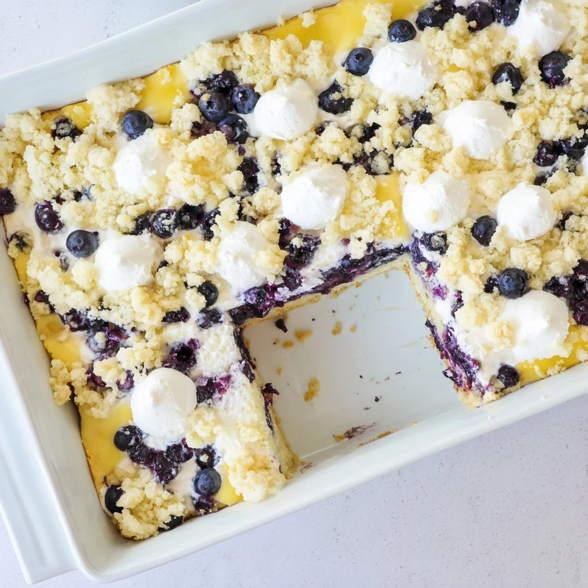 Warm lemon blueberry cheesecake dump cake served fresh from the oven with melted butter drizzle