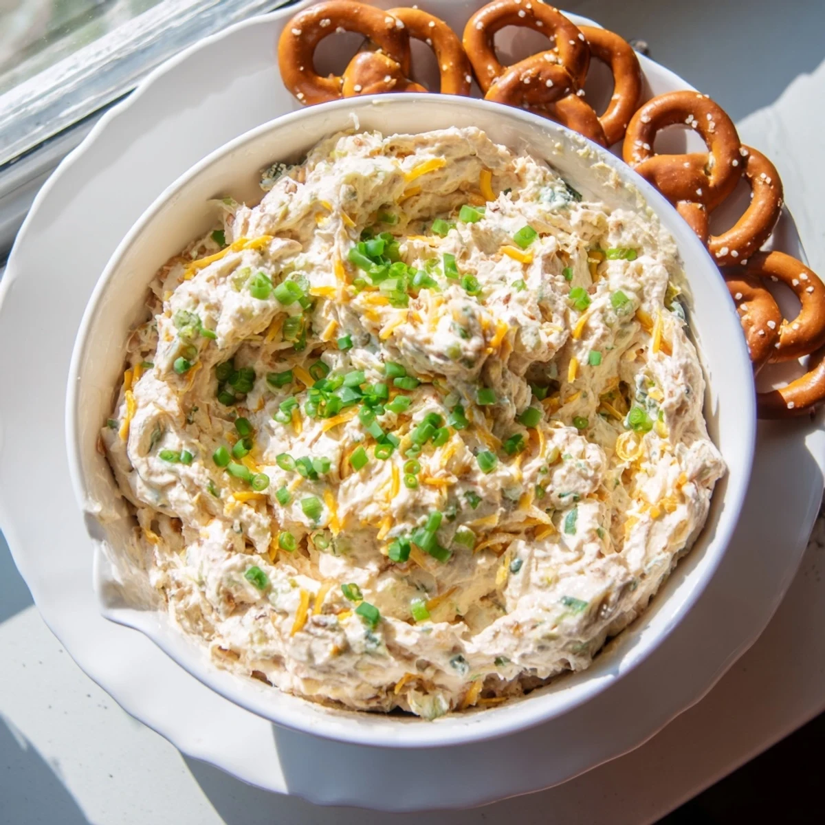 Creamy savory pretzel dip topped with fresh chives served alongside warm soft pretzels