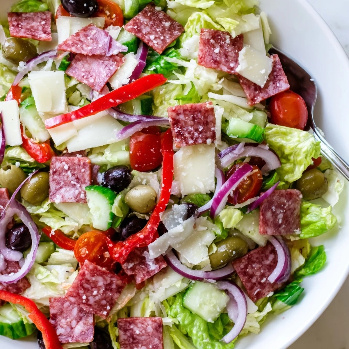 Colorful bowl of Italian chopped salad with fresh vegetables, salami, and tangy homemade dressing