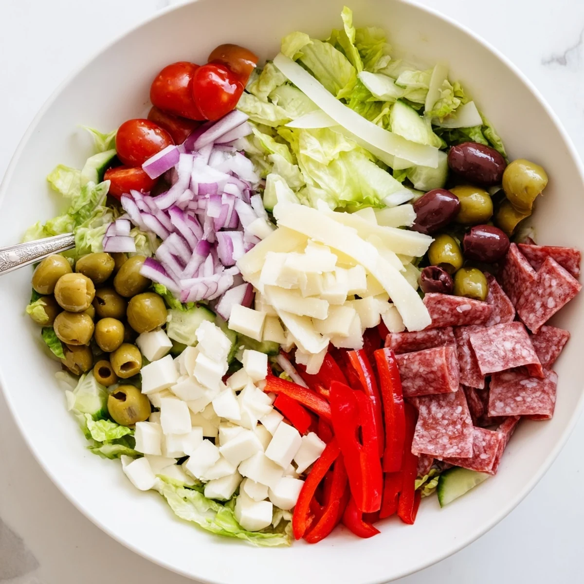 Vibrant Italian chopped salad featuring crisp romaine, tomatoes, olives, and cheese drizzled with zesty dressing