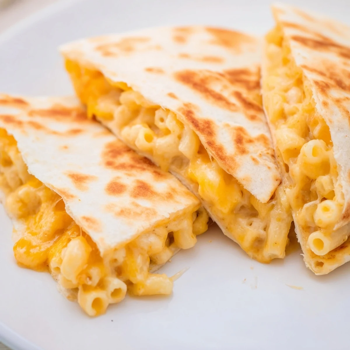 Pan-fried mac and cheese quesadilla with melted cheddar oozing from golden brown tortilla edges