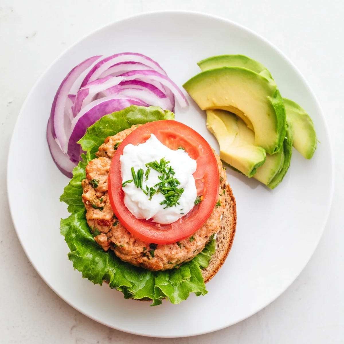 Homemade healthy high protein burger served on a plate with Greek yogurt sauce and crisp vegetable toppings