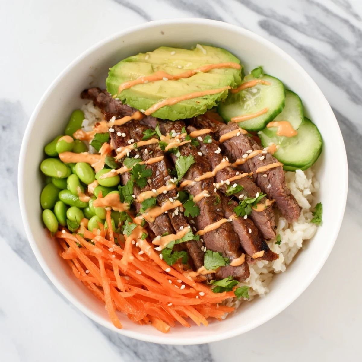 Protein-packed flank steak bowl with marinated grilled steak, avocado, edamame, and crisp veggies atop fluffy jasmine rice