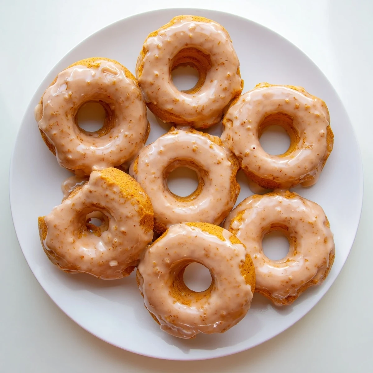 Golden glazed maple pumpkin mochi donuts drizzled with sweet maple icing on a wire rack