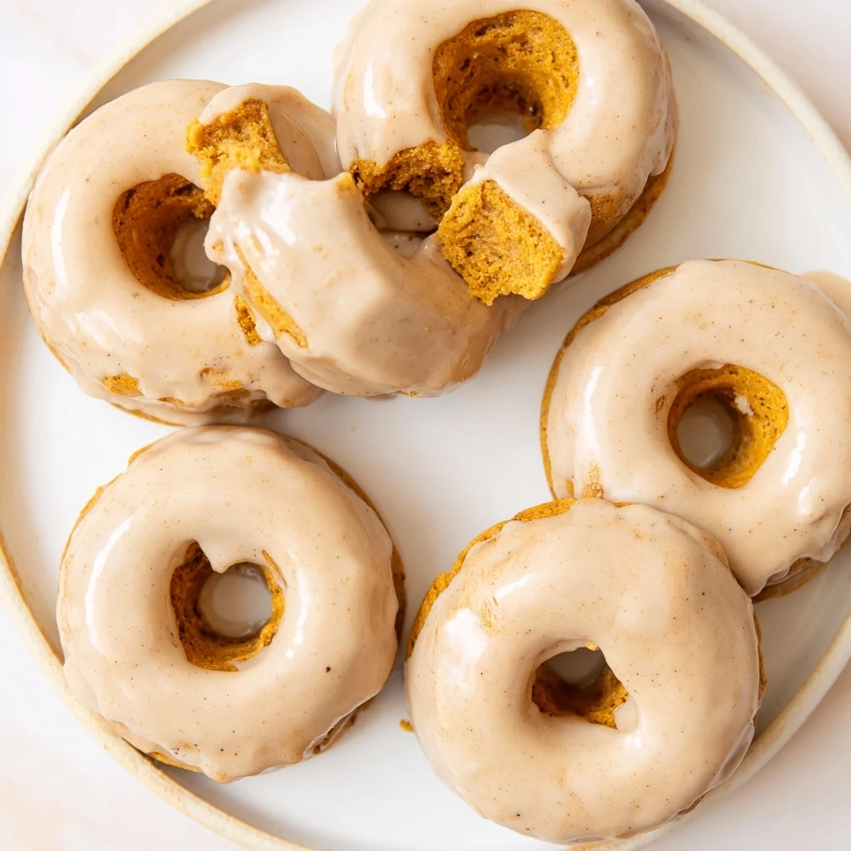 Chewy gluten-free maple pumpkin mochi donuts topped with creamy maple glaze and fall spices