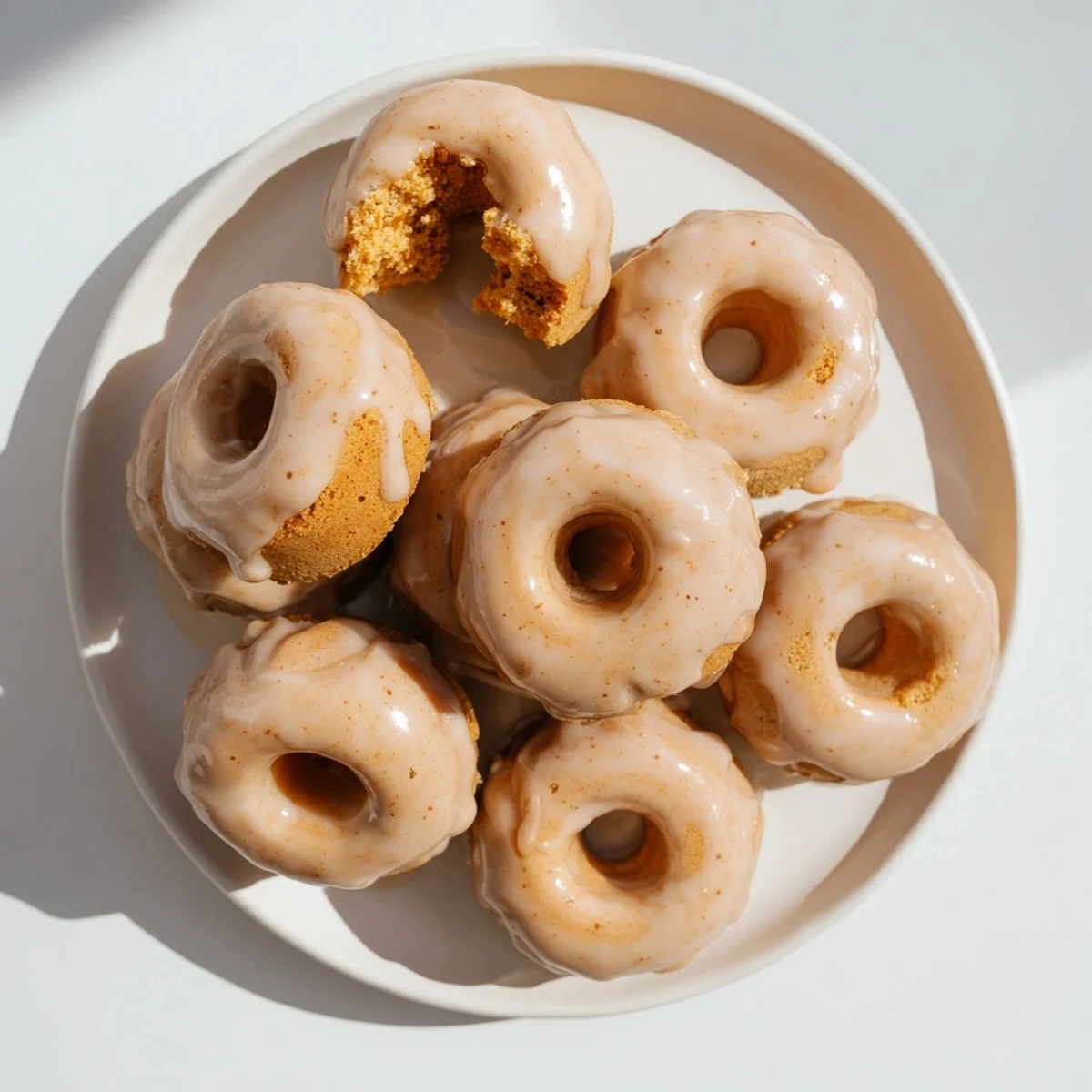 Soft baked maple pumpkin mochi donuts with glossy maple coating on a white serving plate