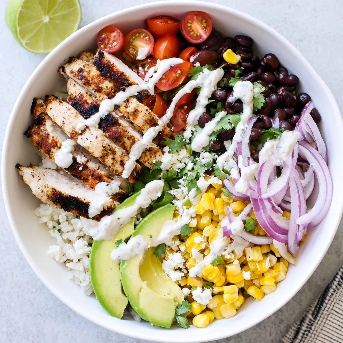 Colorful Ultimate Baja Style Chicken Bowl featuring zesty lime rice, black beans, fresh tomatoes, and creamy dressing