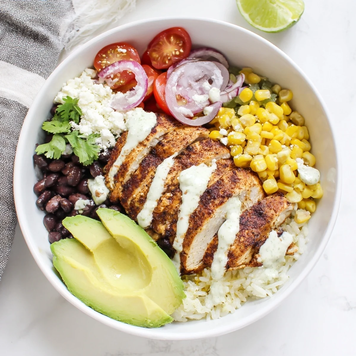 Sliced grilled chicken tops this Ultimate Baja Style Chicken Bowl with avocado, cotija cheese, and crisp vegetables