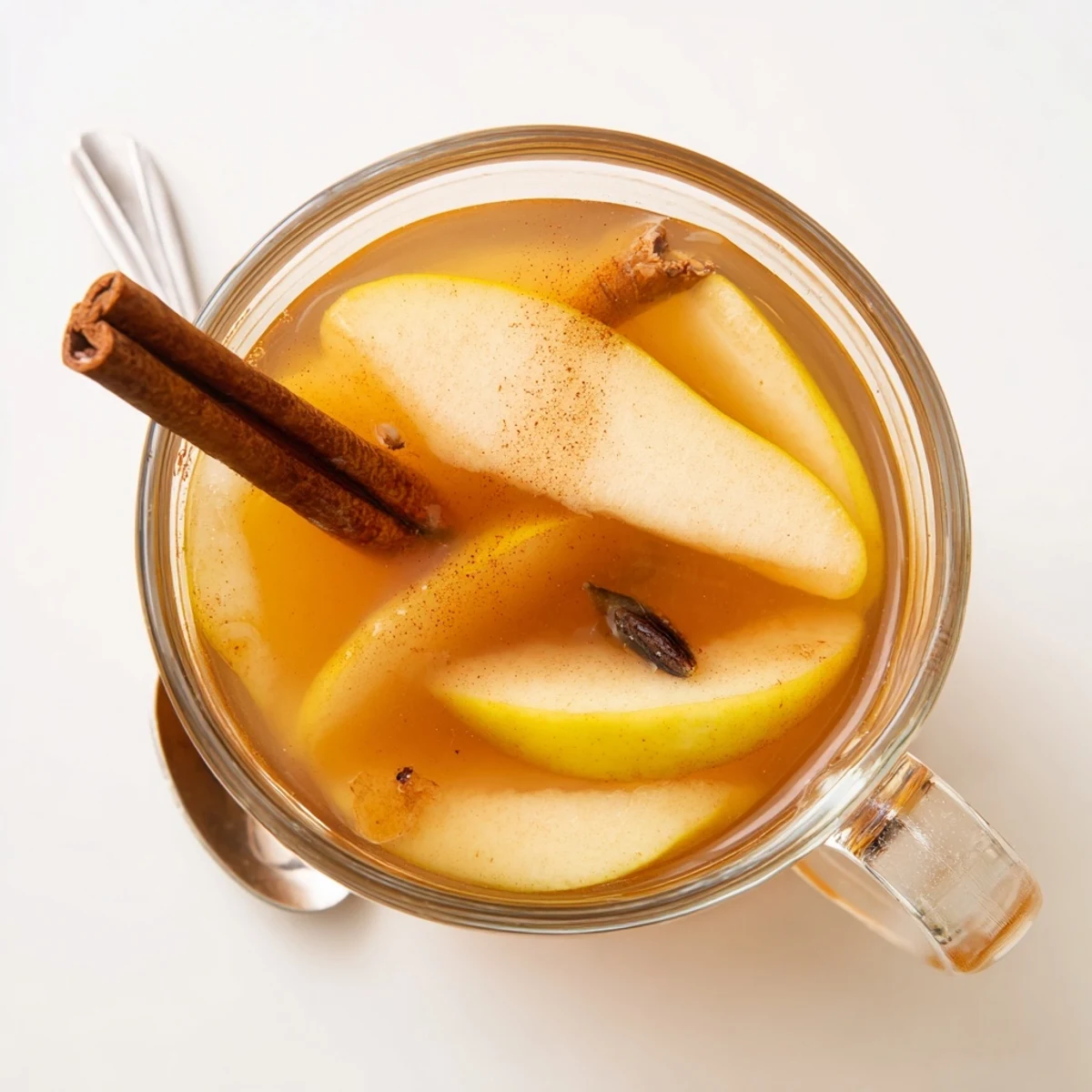 Golden brown pear wedges simmering in spiced apple cider with whole cinnamon sticks