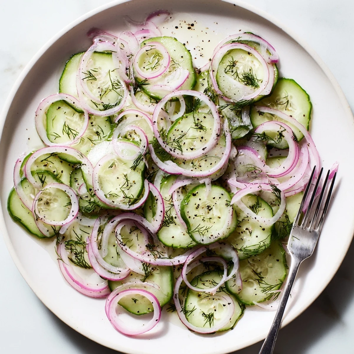 Crisp refreshing cucumber salad plated with light olive oil vinaigrette and fresh herbs for summer gatherings