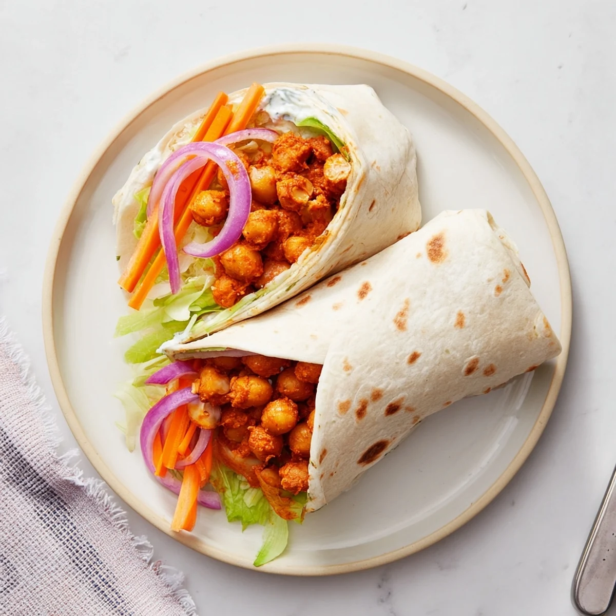 Golden tortilla wrap stuffed with spicy buffalo chickpeas and crisp fresh lettuce