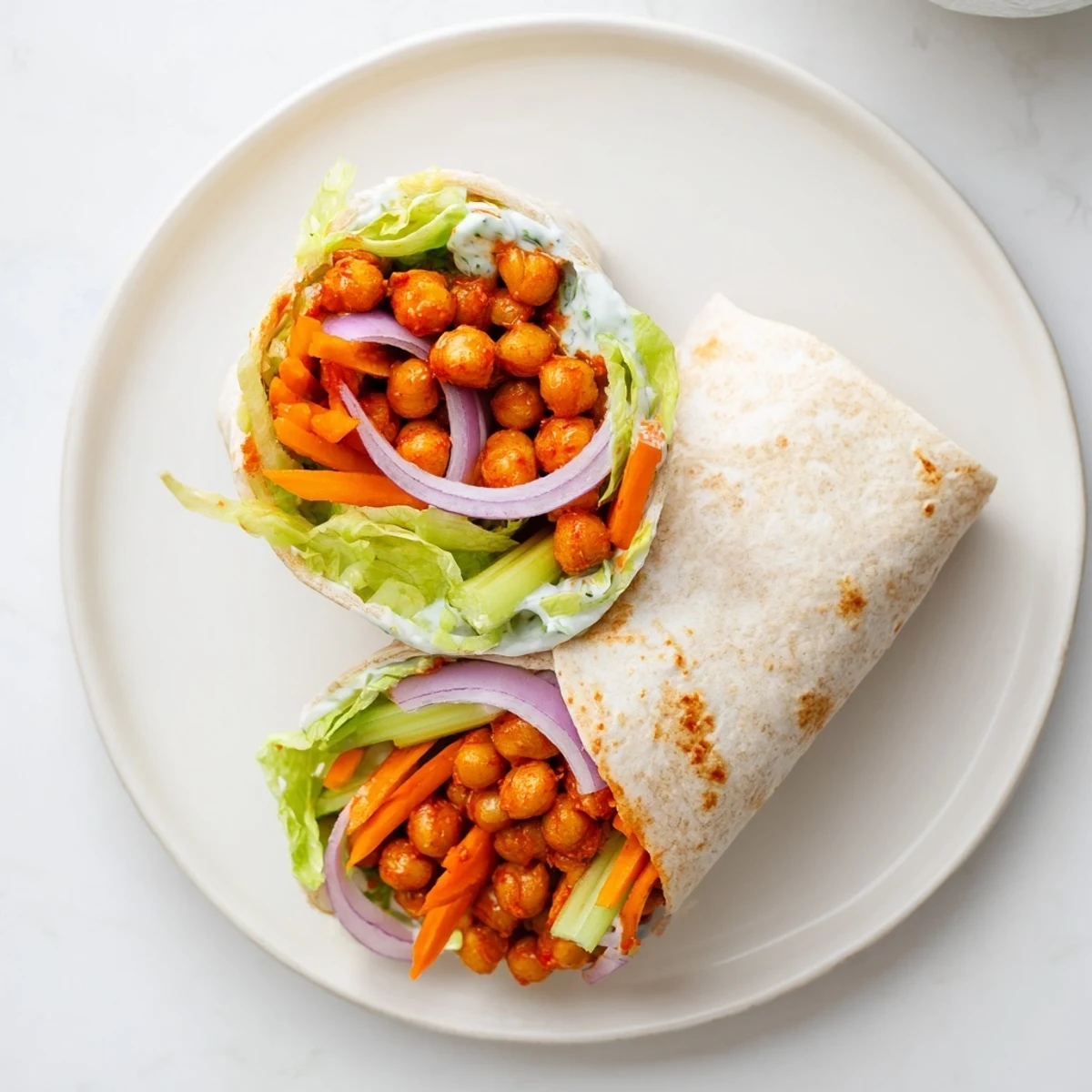 Spicy buffalo chickpea wrap rolled with crunchy vegetables and creamy ranch dressing