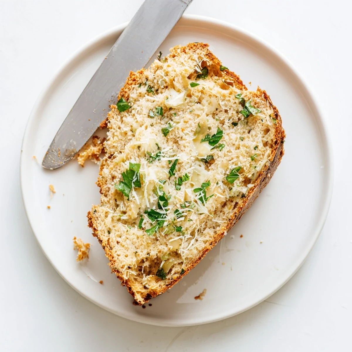 Golden brown Parmesan herb keto bread loaf topped with melted cheese and fresh parsley