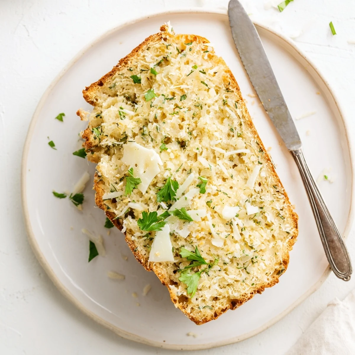 Homemade keto bread with Parmesan crust and rosemary garnish on wooden cutting board