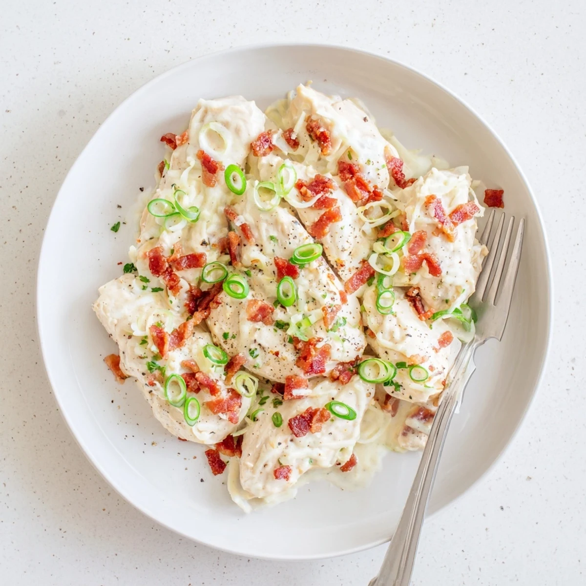 Golden cheesy Crockpot Million Dollar Chicken topped with crispy crumbled bacon bits