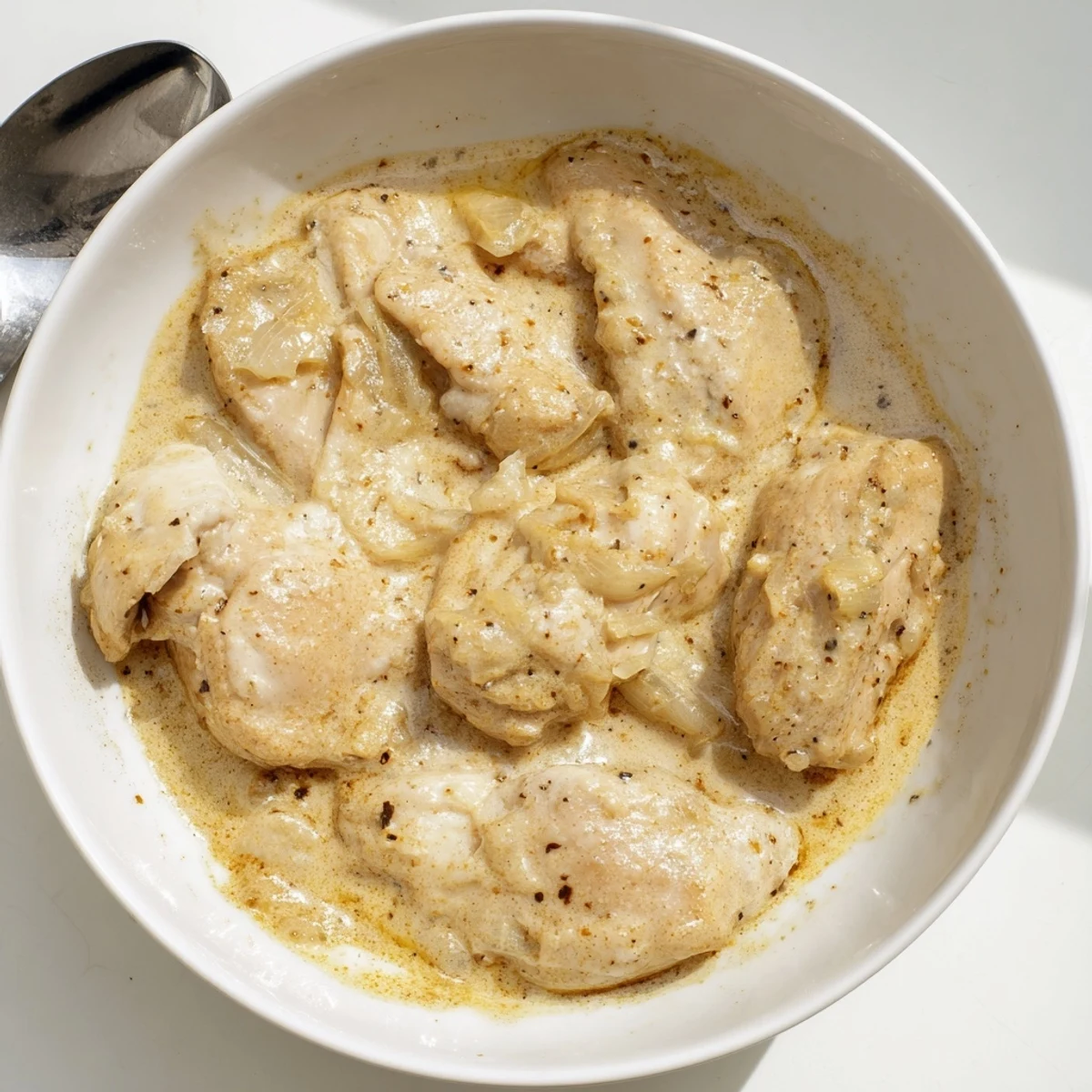 Golden brown chicken thighs swimming in a rich, velvety crockpot creamy gravy sauce