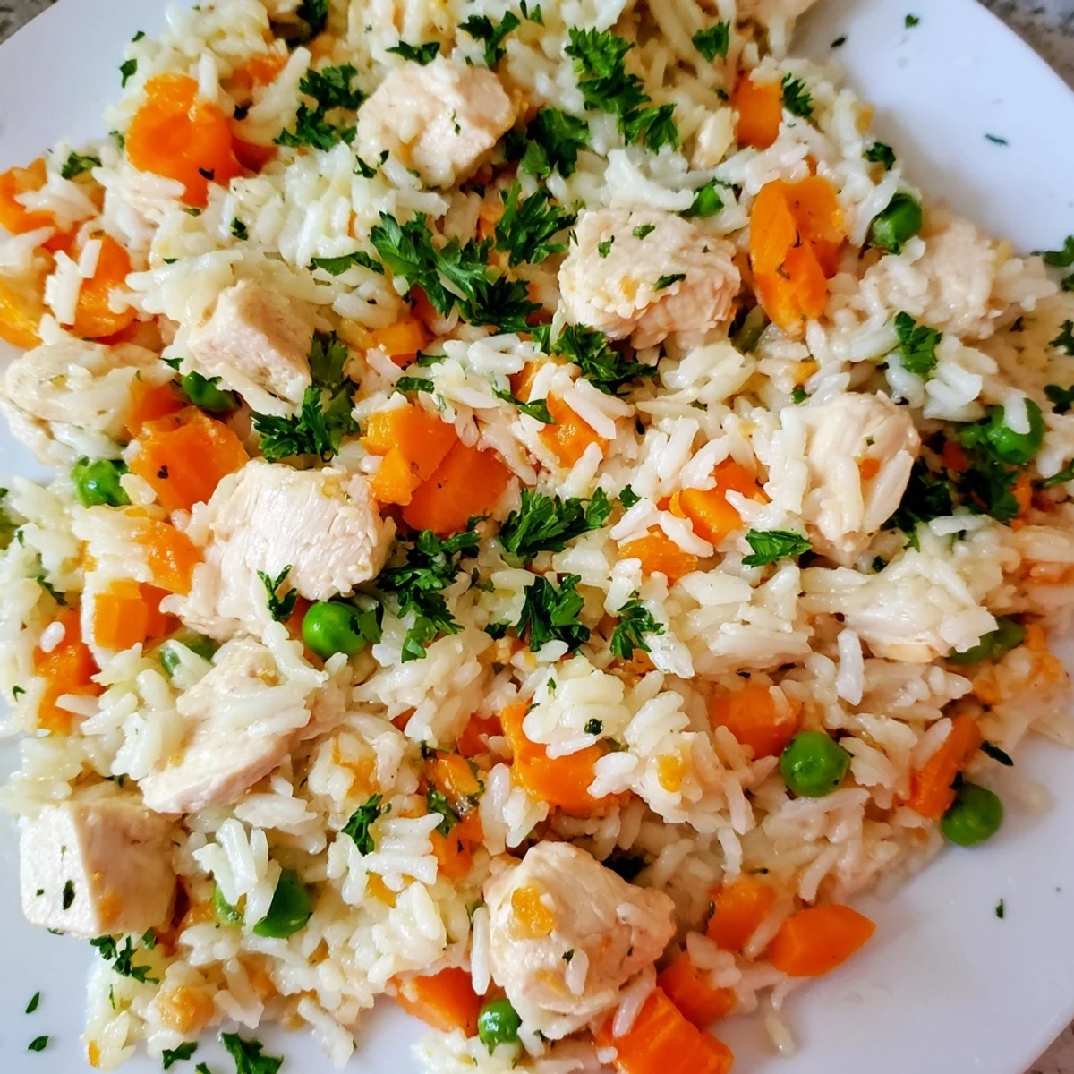 Tender chicken pieces nestled between fluffy white rice and colorful vegetables in this comforting one-pot meal