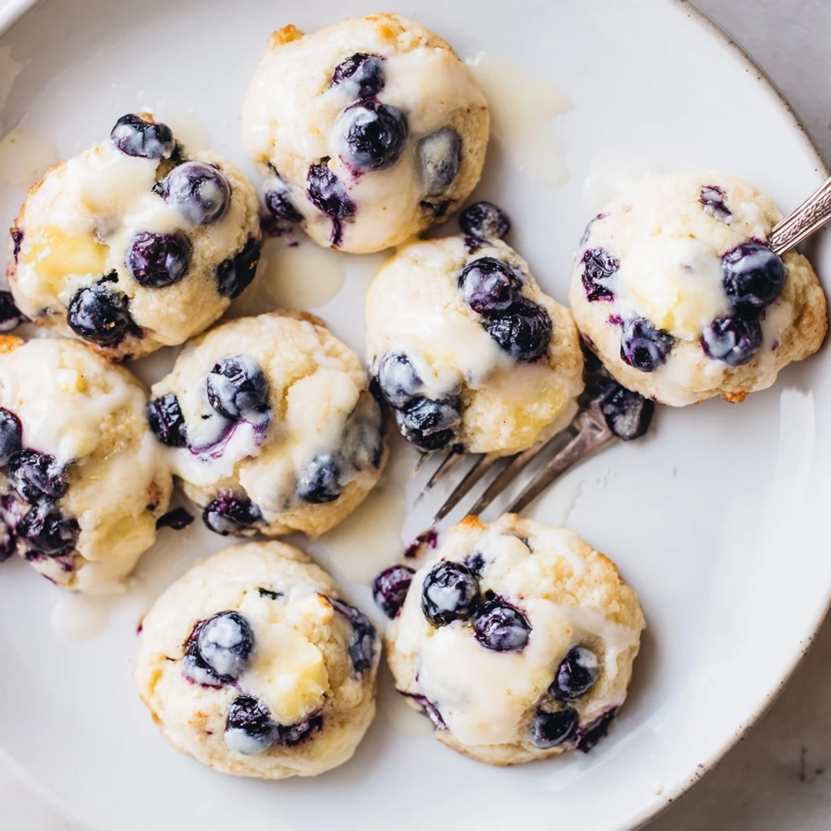 Golden lemon blueberry cheesecake cookies with creamy centers and fresh blueberry streaks on a white plate