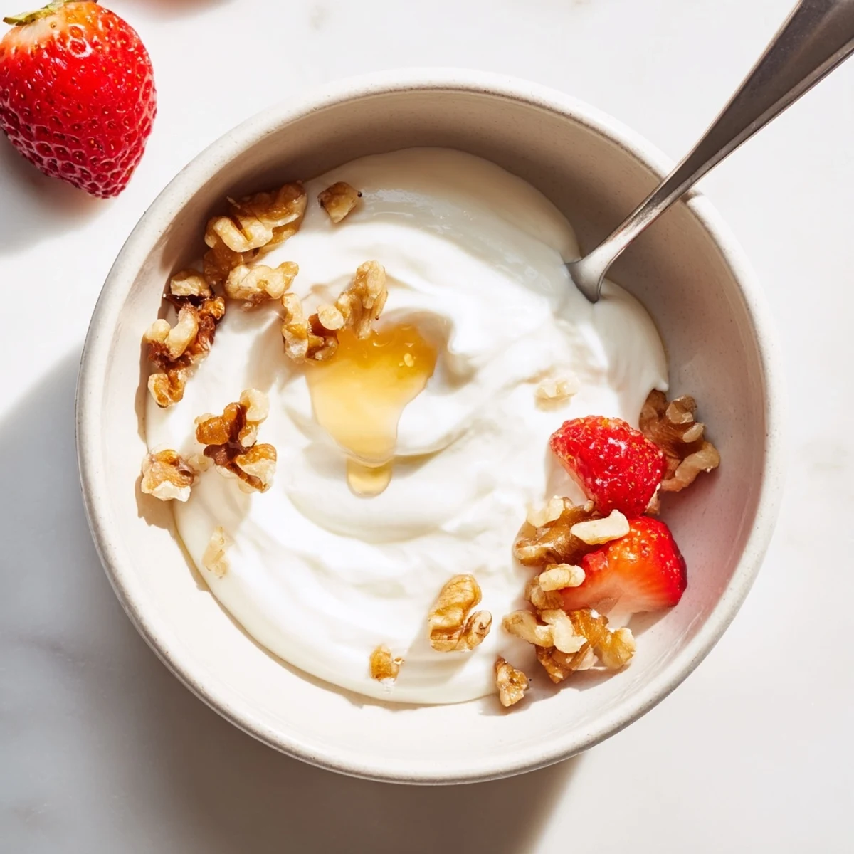 Creamy homemade Greek yogurt topped with fresh honey, ripe berries, and crunchy granola for breakfast