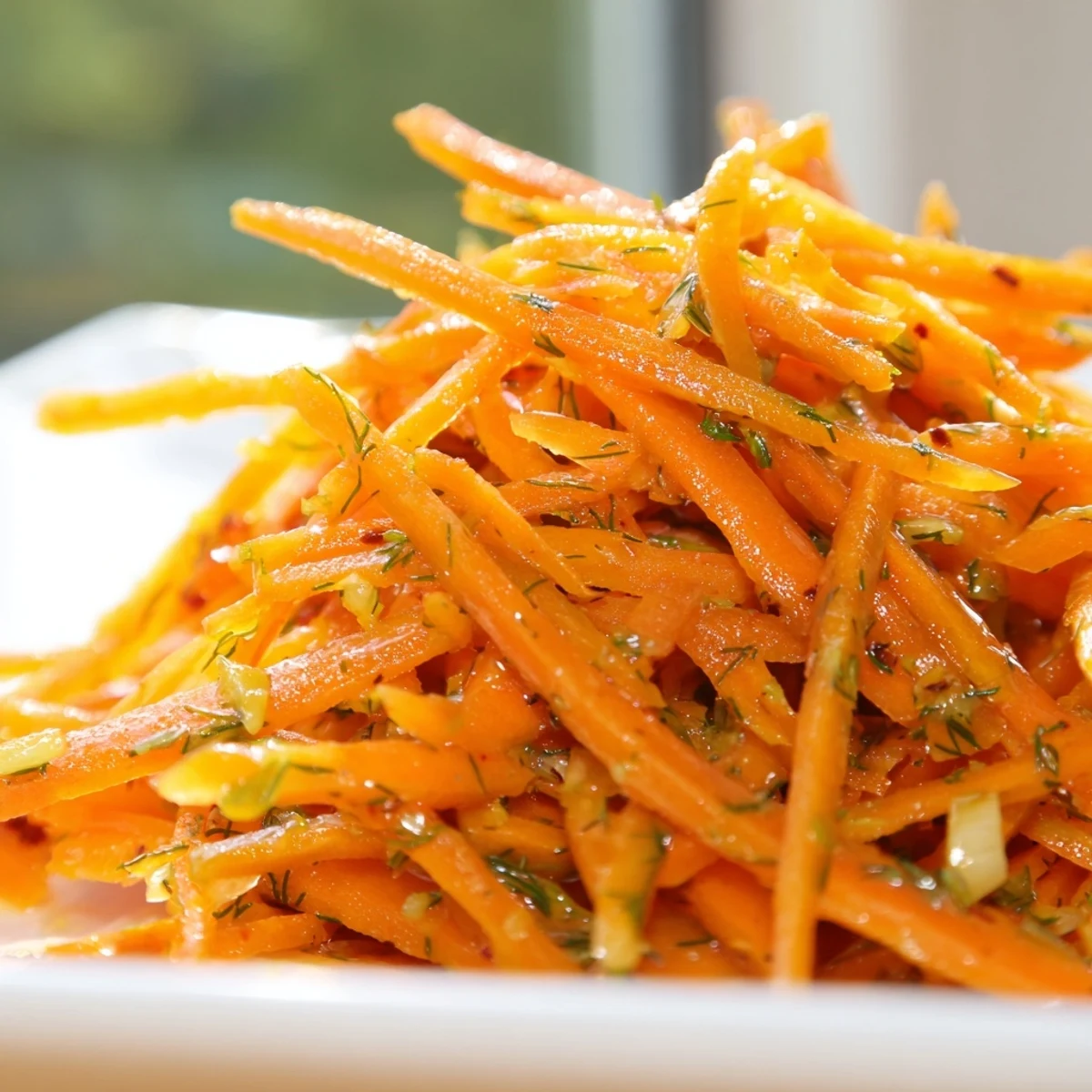 Marinated Lemon Dill Carrot Salad in a white bowl with fresh herb garnish