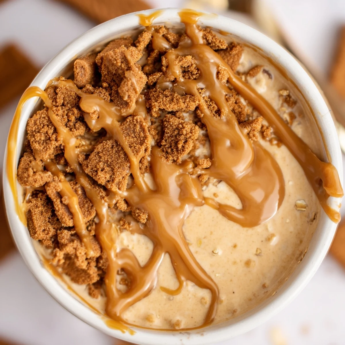 Biscoff overnight oats layered with cookie crumbles and smooth caramelized swirl in morning light