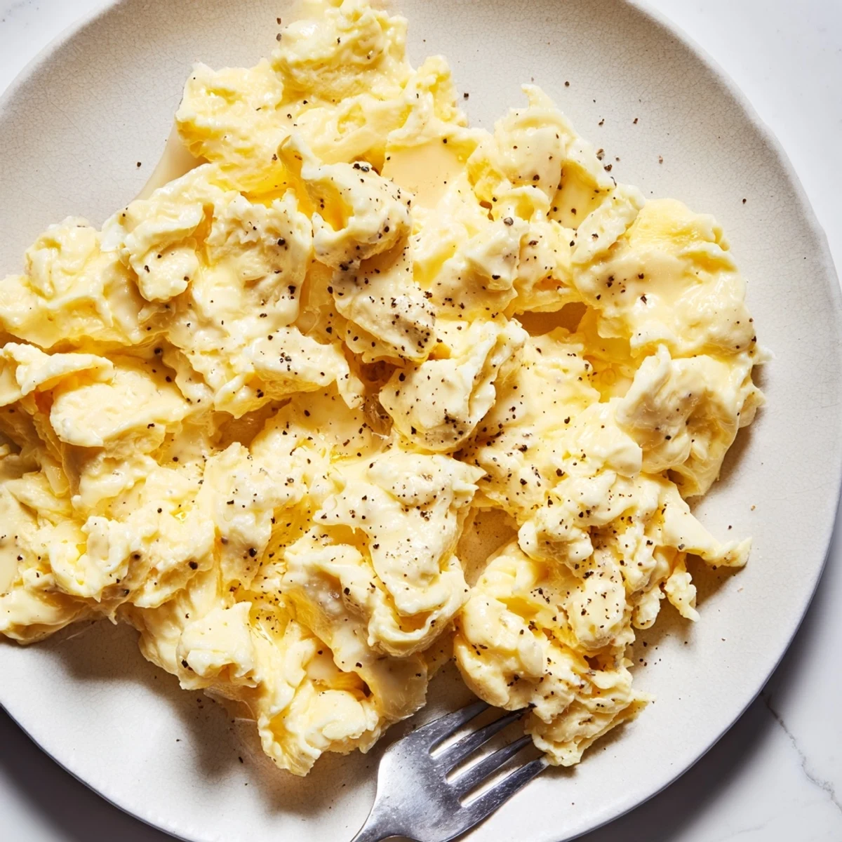 Fluffy scrambled eggs served steaming hot in a skillet alongside toasted bread and fresh herbs