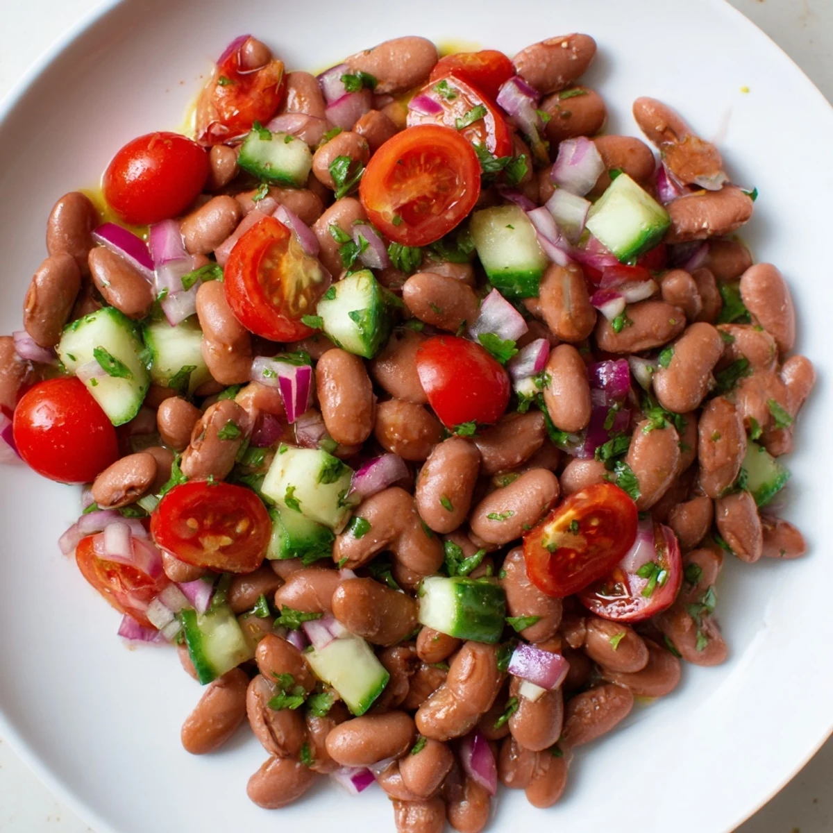 Fresh pinto bean salad topped with halved cherry tomatoes and diced cucumber