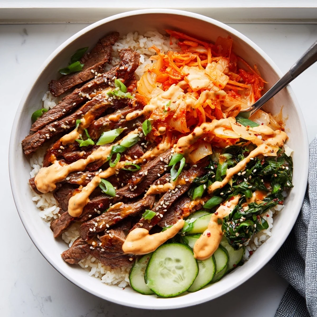 Caramelized sliced steak atop colorful shredded toppings in Korean BBQ steak rice bowls