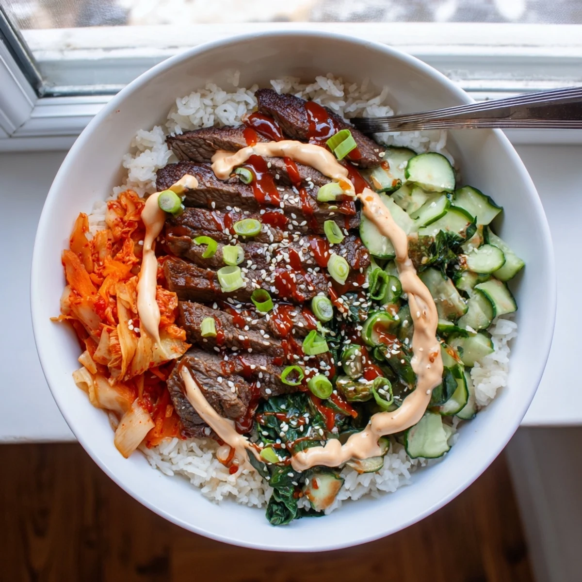 Korean BBQ steak rice bowls drizzled with creamy spicy sauce over warm jasmine rice