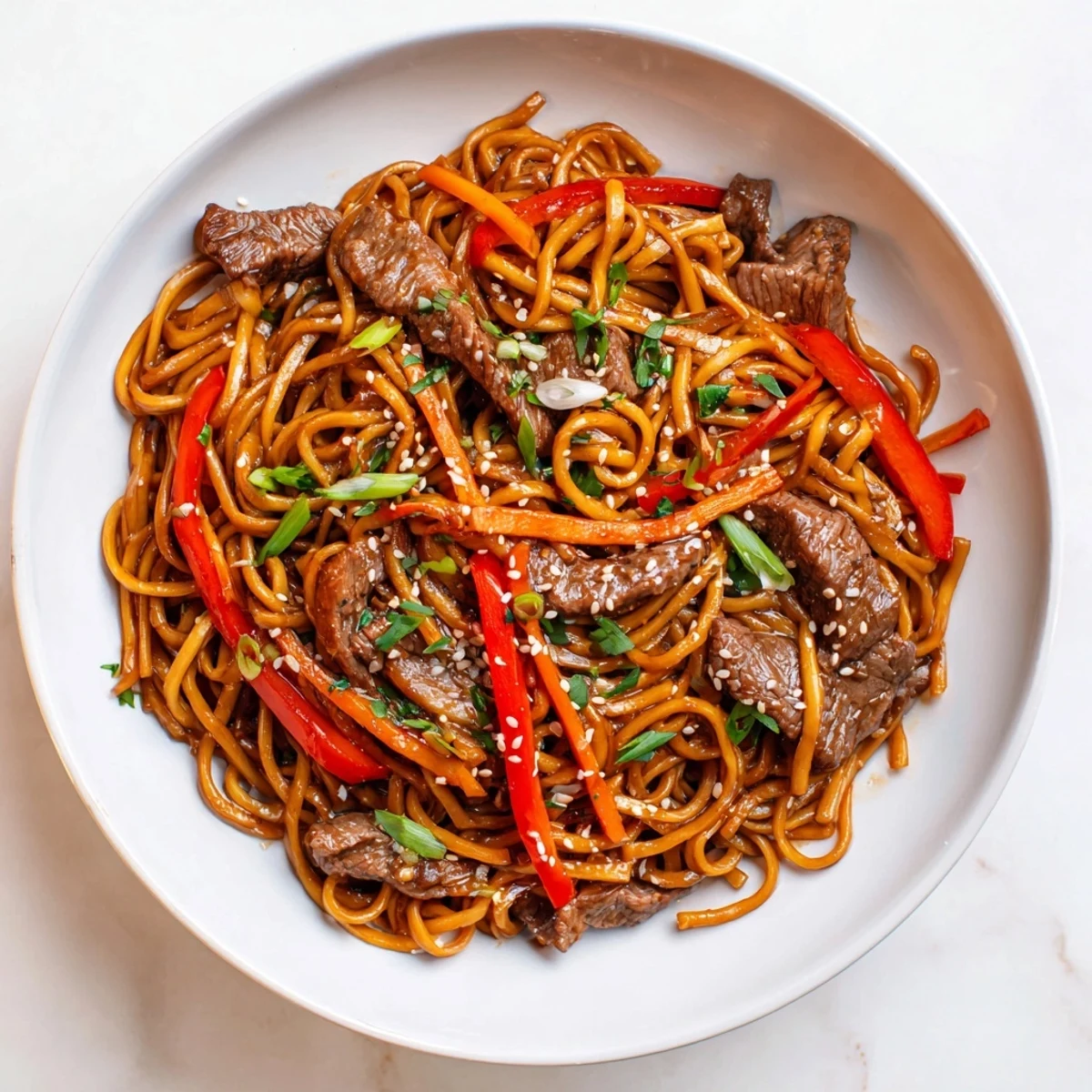 Sticky Beef Noodles glistening with glossy sauce, tender beef and spring onions.