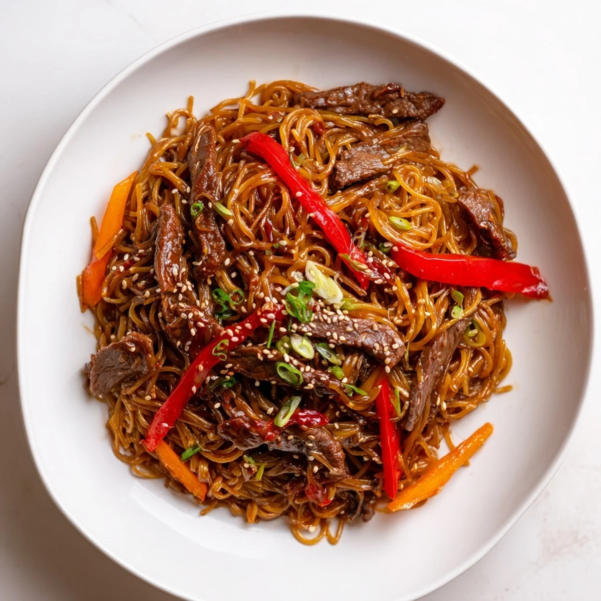 Weeknight Sticky Beef Noodles served in bowl, sesame seeds and cilantro.