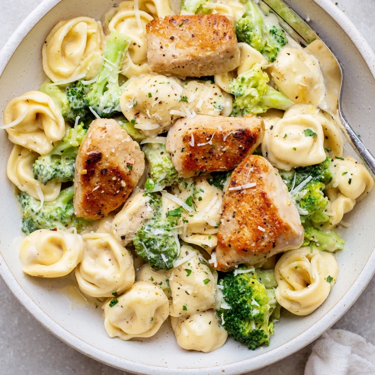 Creamy Garlic Parmesan Tortellini Chicken Broccoli Recipe showing golden chicken, steaming cream sauce