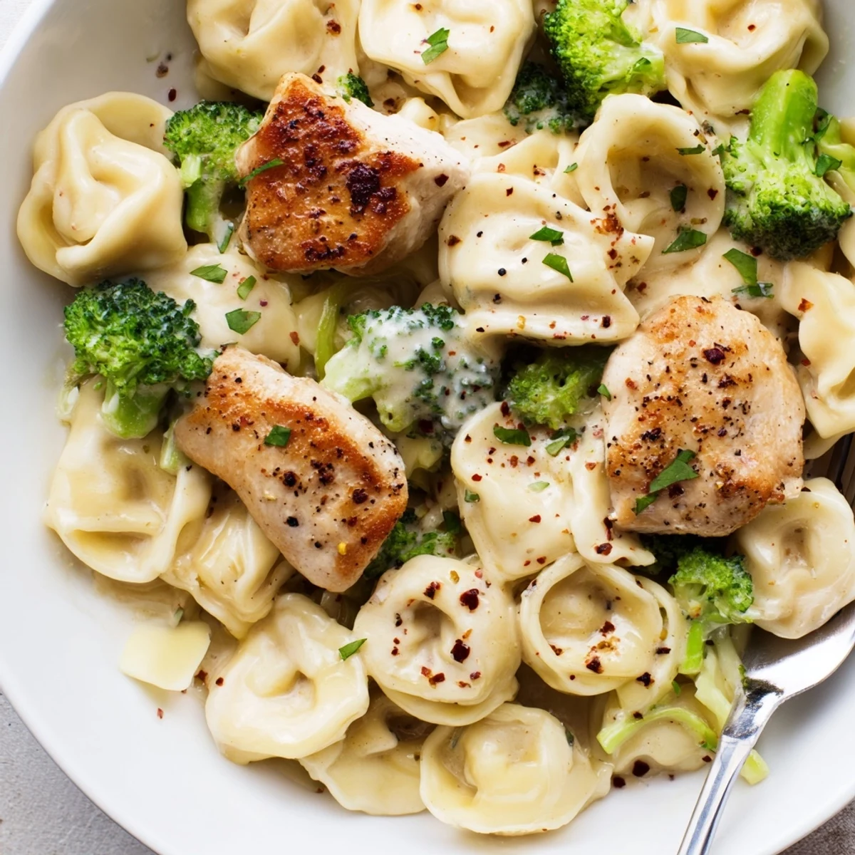 Skillet-tossed and saucy, Creamy Garlic Parmesan Tortellini Chicken Broccoli Recipe garnished with parsley