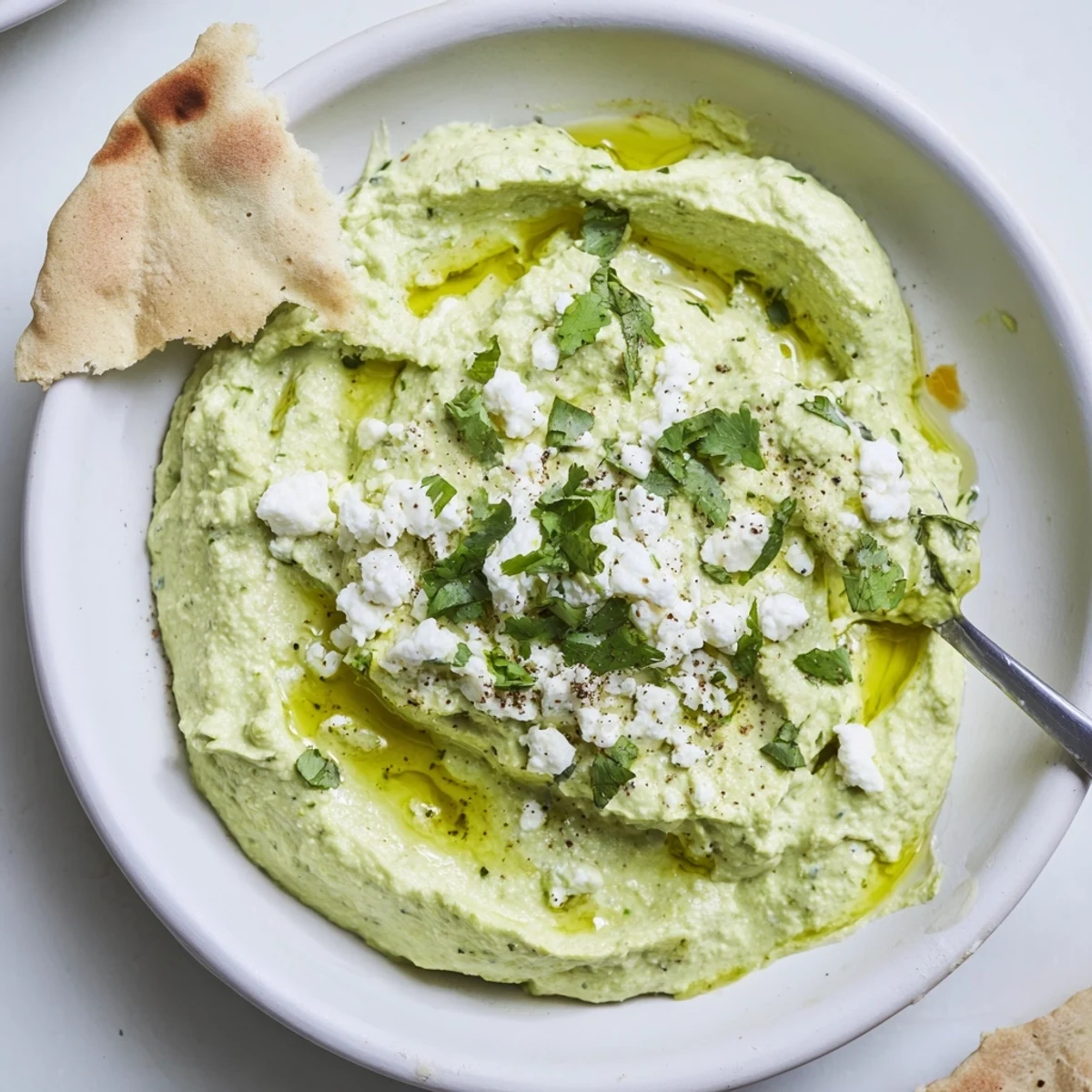 Party ready Creamy Avocado Feta Dip with pita chips and cilantro garnish  
