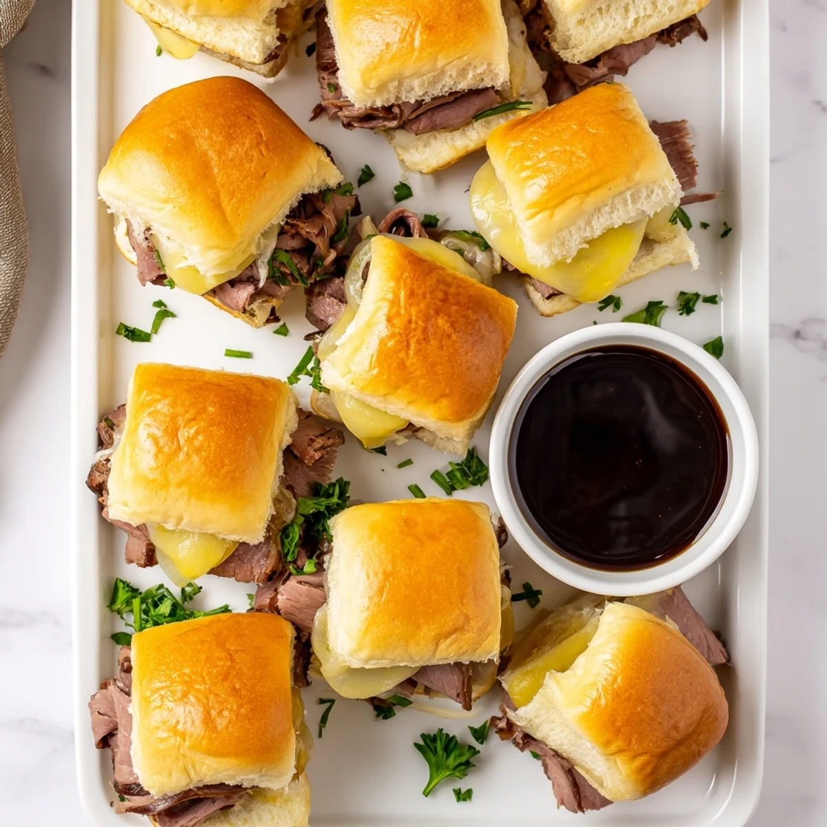 Golden French dip sliders loaded with tender roast beef and melted provolone cheese on toasted rolls