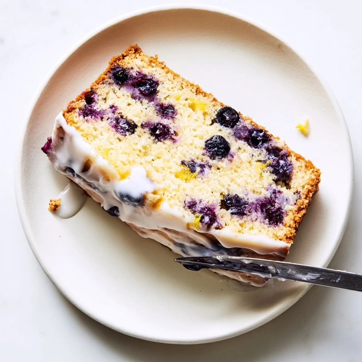 Freshly baked lemon blueberry cake with vibrant blueberries and tangy lemon glaze on serving board