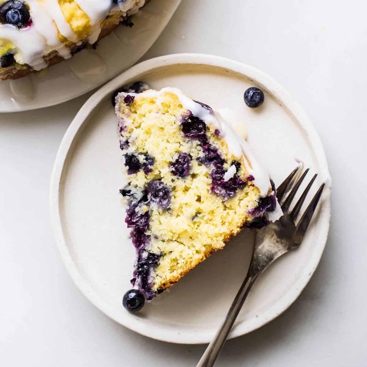 Moist lemon blueberry cake studded with purple berries and topped with sweet lemon icing