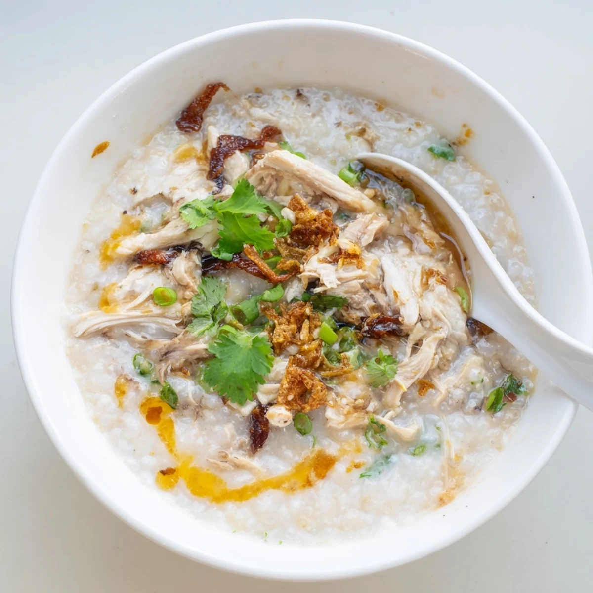 Steaming Chinese chicken congee porridge with tender shredded chicken and vibrant green onions for a comforting breakfast