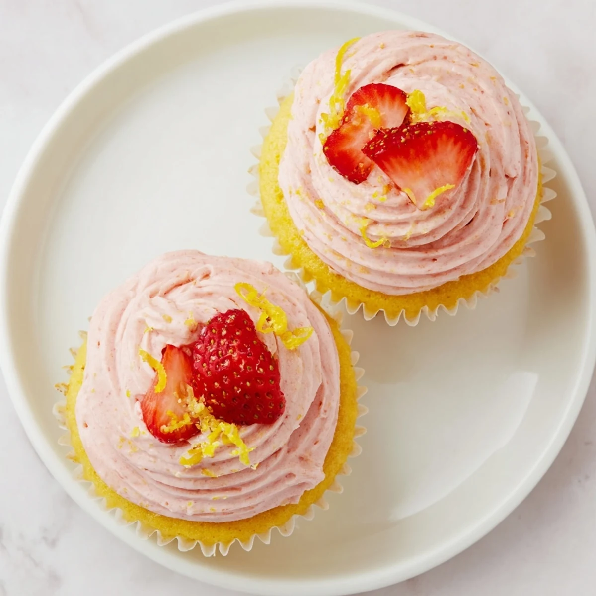 Light and fluffy lemon cupcakes swirled with creamy strawberry frosting and fresh strawberry halves