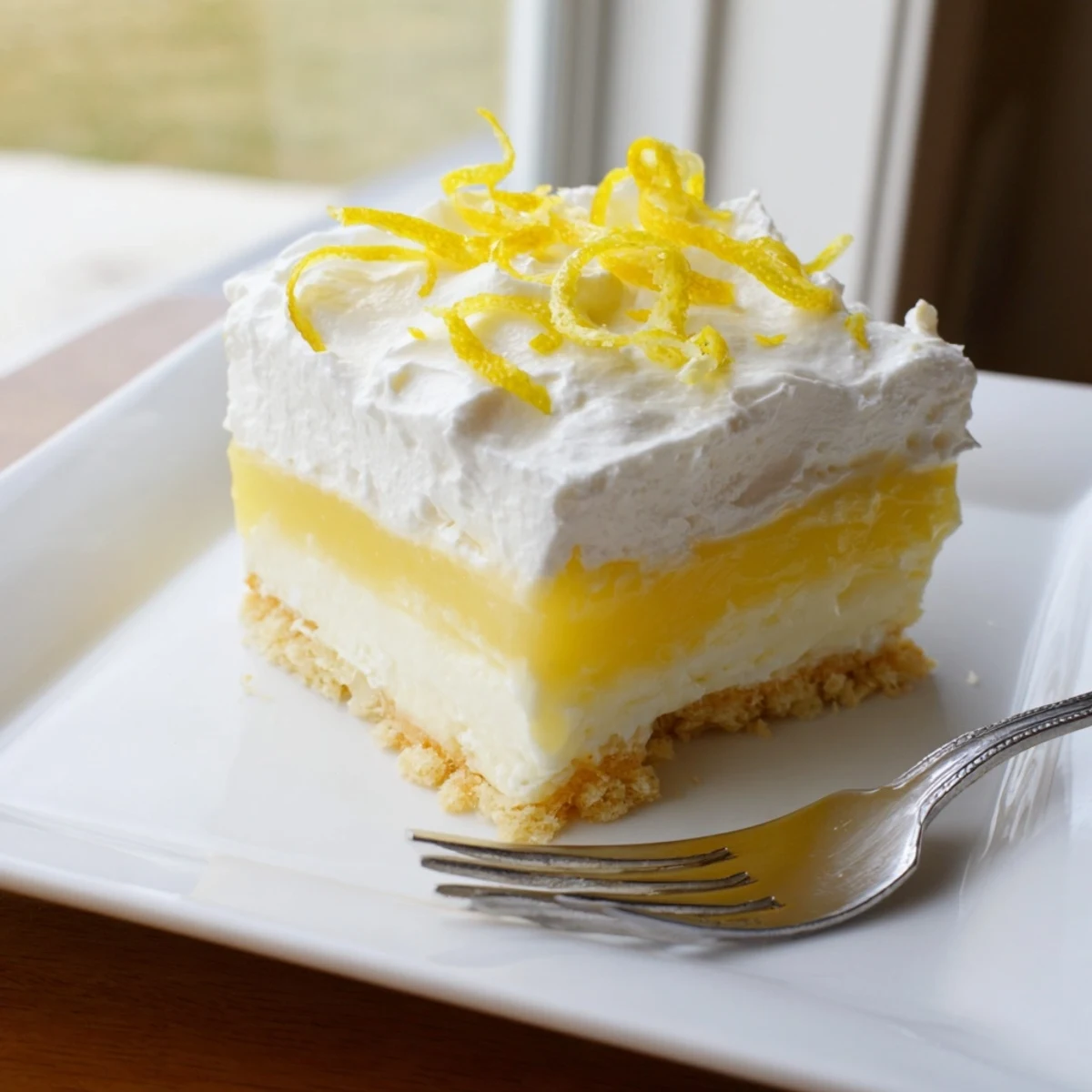 Creamy layered lemon lush dessert bar with tangy pudding filling and buttery golden crust